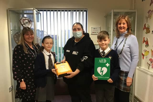 Sharon Cliff (left), acting head of Larkholme Primary School, with school parent Helen Crane (centre), Debbie Atkinson, chairman of governors and two pupils, as Helen presents a defibrillator to the school.