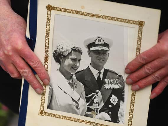 A person holds a photograph of Queen Elizabeth II and the Duke of Edinburgh outside Windsor Castle, Berkshire, following the announcement of his death at the age of 99. Picture date: Friday April 9, 2021. Picture: PA Wire/PA Images/Victoria Jones