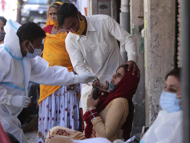 A health worker takes a nasal swab sample to test for Covid-19 in Jammu, India