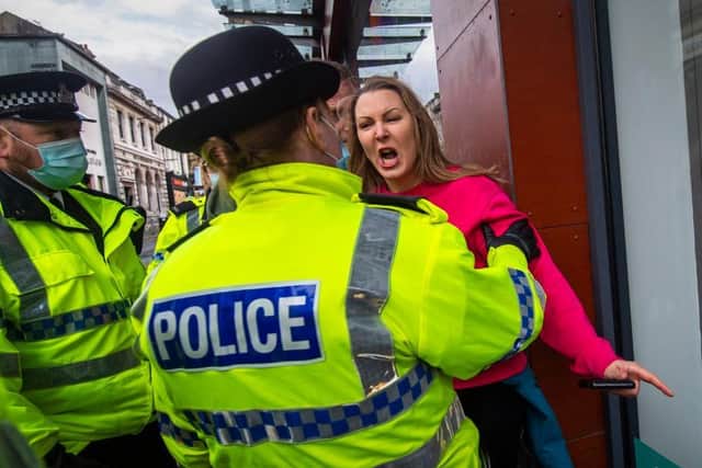A woman without a face mask shouts and gestures towards police officers during an anti lockdown protest on November 14, 2020 in Liverpool