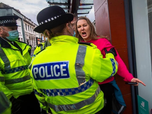 A woman without a face mask shouts and gestures towards police officers during an anti lockdown protest on November 14, 2020 in Liverpool