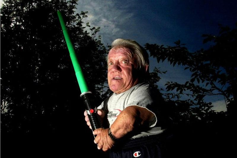 R2D2 actor Kenny Baker poses at his home in Preston with a light sabre for the 30th anniversary of the release of Star Wars: A New Hope