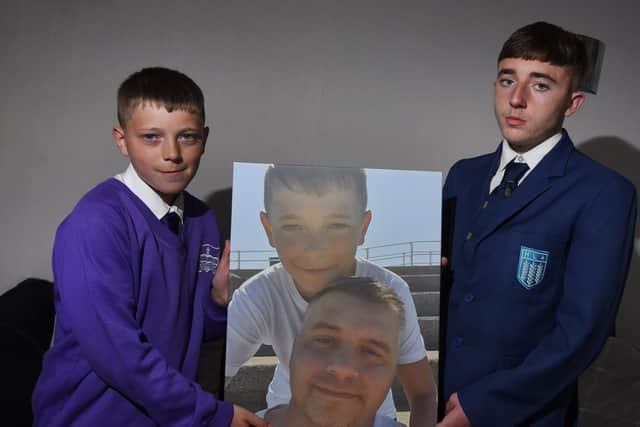 Kai Ryder, 11, with older brother Haydyn, holds his favourite photograph of him and his dad, Rob Ryder, who died of cancer.