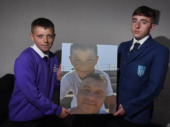 Kai Ryder, 11, with older brother Haydyn, holds his favourite photograph of him and his dad, Rob Ryder, who died of cancer.