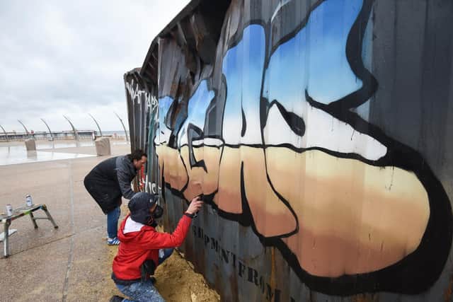 Graffiti artists Christian Seca One and Graham Morriss working on a crate on the Comedy Carpet.