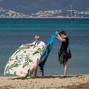 A tourist couple unfold their towels on Palma Beach in Palma de Mallorca