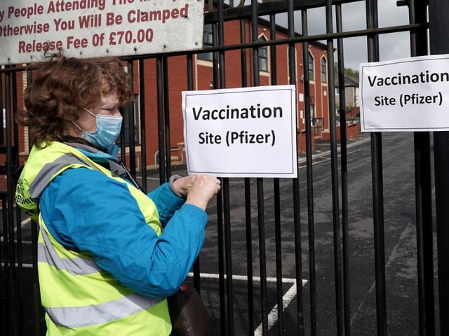 A volunteer gives puts up signs outside a mobile vaccination clinic set up at the Masjid E Sajedeen Mosque in Little Harwood on May 24, 2021 in Blackburn