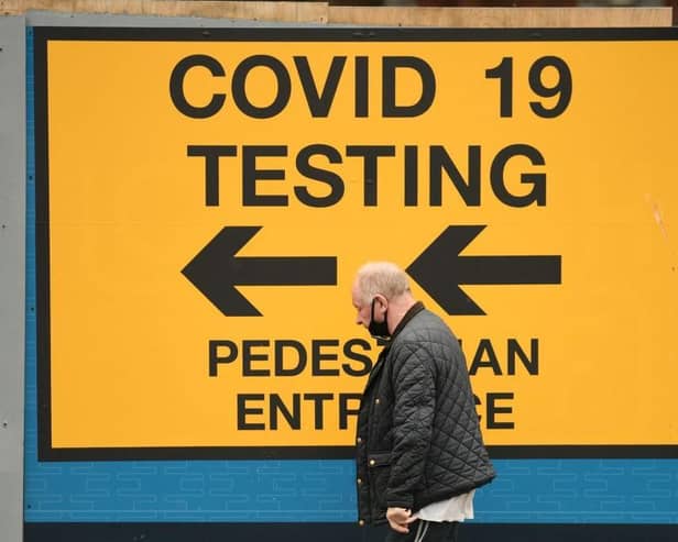 A pedestrian walks past a sign directing members of the public to a Covid-19 testing centre in Bolton,