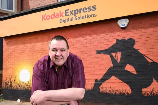 John Ormston has opened Kodak Express and Cable Express on Highfield Road. Here with the mural done by Blackpool street artist Seca One