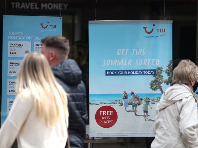 People make their way past the shop window of a Tui store