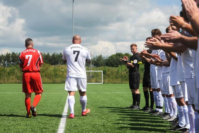 Jordan Banks' step-dad Daniel and dad Matt are applauded onto the pitch during a charity match in the youngster's memory. Photo: Daniel Martino/JPI Media