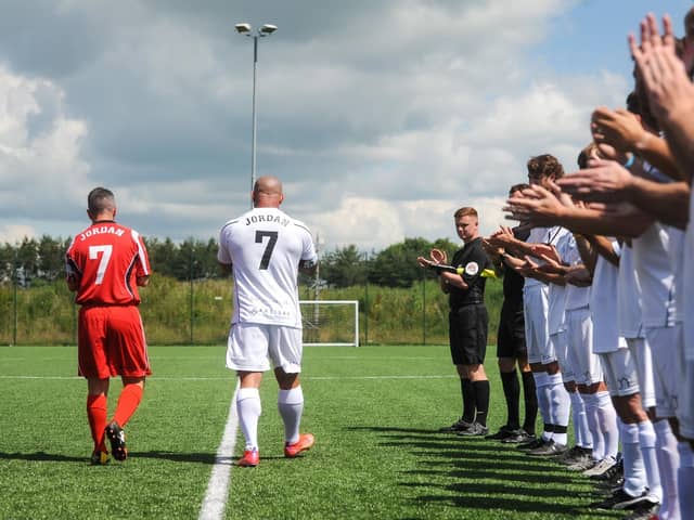 Jordan Banks' step-dad Daniel and dad Matt are applauded onto the pitch during a charity match in the youngster's memory. Photo: Daniel Martino/JPI Media