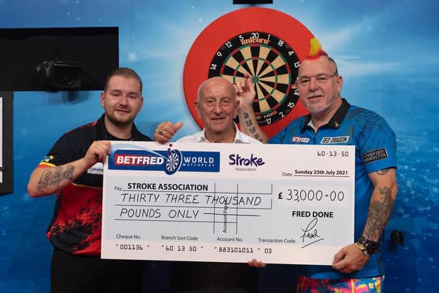 World Matchplay champion Peter Wright (right), runner-up Dimitri Van den Bergh (left) and Betfred boss Fred Done with the cheque for the Stroke Association