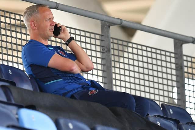 Neil Critchley on his phone in the stands prior to kick-off