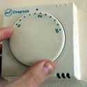 A gas central heating thermostat being adjusted.