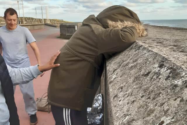Roy Wilson struggles to get up and holds onto the sea wall at Blackpool