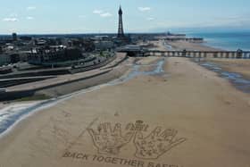 Members of the public contribute personalised messages to their loved-ones on a 40-metre sand drawing by artists ‘Sand in Your Eye’, which has been created by hygiene brand Carex to encourage people to get back together safely, Blackpool. Picture by Kestral-Cam