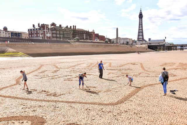Members of the public contribute personalised messages to their loved-ones on a 40-metre sand drawing by artists ‘Sand in Your Eye’, which has been created by hygiene brand Carex to encourage people to get back together safely, Blackpool. Picture by Anthony Devlin/PA Wire