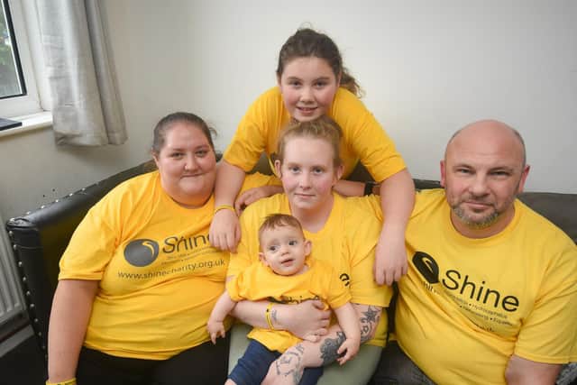 10-month-old Ava, who has spina bifida and survived a string of serious health issues,  is pictured with, godmother Kelly-Ann Mason, mum Emma Cowley, big sister Ella  and godfather Paul Mason..
