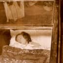 One of the starving brides of Blackpool sleeps in her glass box, watched by curious onlookers. Numerous similar public displays were recently banned. (Photo by Keystone/Getty Images)