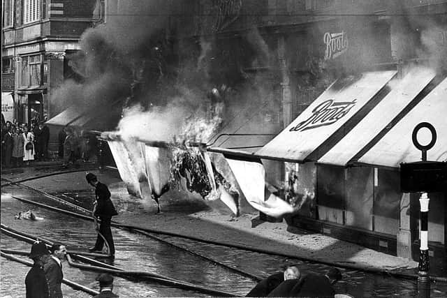 The earlier stages of the fire when there was still hope of saving the block of buildings. The flames are seen catching the sun blinds on Market Street