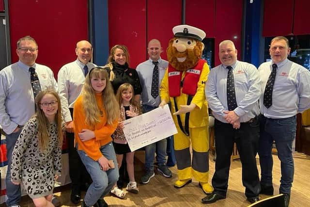 Hazel Tipping and her daughters present the cheque to RNLI members and mascot, Stormy Stan