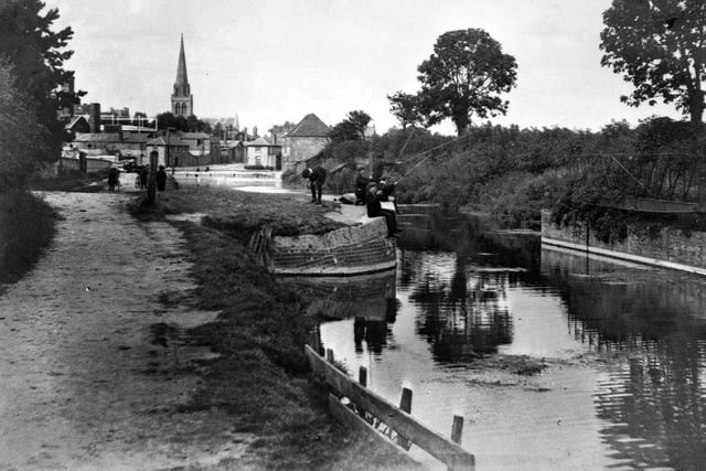 Boys fishing in Chichester Canal in the late 19th century, with the gasometers of Chichester Gas Works in the background