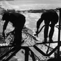 Balancing on girders high above the promenade workmen repair Blackpool Tower, 1934