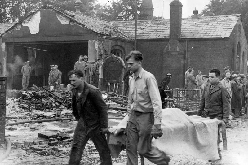 Grim faced rescuers remove a body from the ruined school