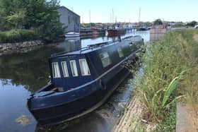 A canal boat tilted in low water on the Glasson branch of the Lancaster Canal's approaching Glasson Marina.