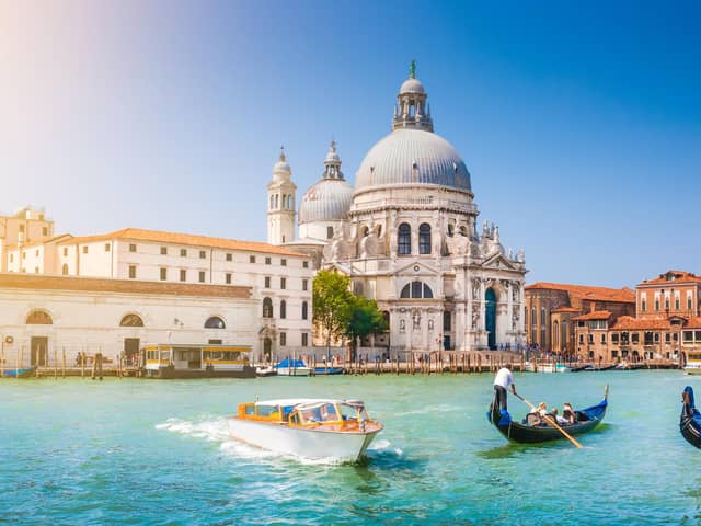 Beautiful view of traditional Gondola on Canal Grande with historic Basilica di Santa Maria della Salute in the background on a sunny day in Venice, Italy