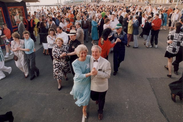 Pat and Ken Rayner (front) lead 200 dancers quickstepping along the Golden Mile for charity