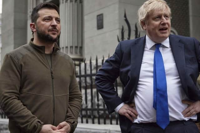 In this image provided by the Ukrainian Presidential Press Office, Ukrainian President Volodymyr Zelenskyy, left, and Britain's Prime Minister Boris Johnson talk during their walk in downtown Kyiv, Ukraine