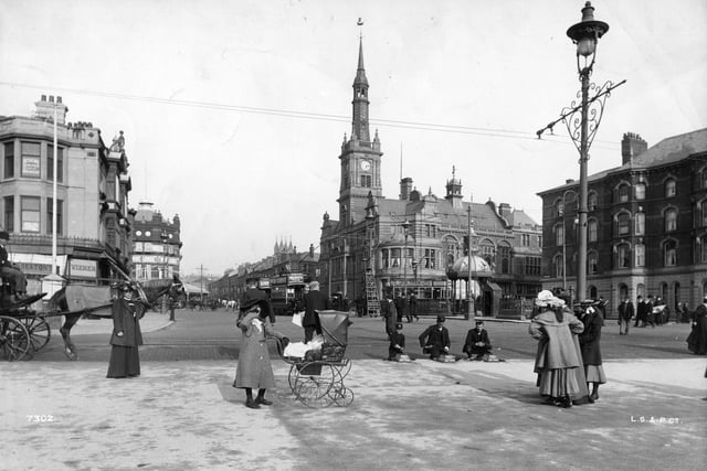 A child with a pram on the streets of Blackpool with the Town Hall in the background