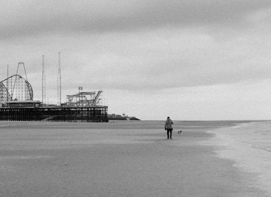 South Pier and the looming Big One in the background as a dog walker stolls on the beach. Emilia Zogo