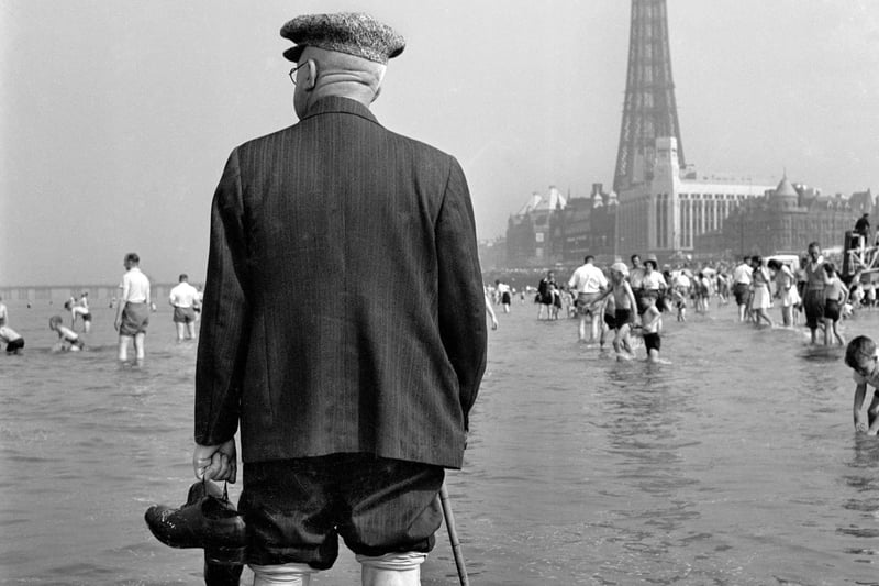 An elderly man paddles in the sea with Blackpool Tower in the background. Photo: John Gay/Historic England/Mary Evans