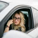 A mother waits in her car near a school — but stopping in restricted zones during the school run could still lead to fines or penalty points under UK parking laws.