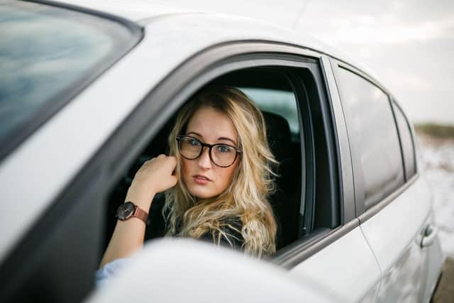 A mother waits in her car near a school — but stopping in restricted zones during the school run could still lead to fines or penalty points under UK parking laws.