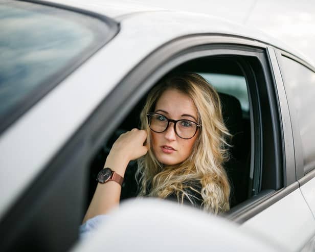 A mother waits in her car near a school — but stopping in restricted zones during the school run could still lead to fines or penalty points under UK parking laws.