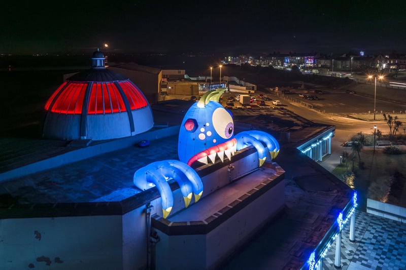 Chomper, a giant illuminated monster, peeping out of the roof of Marine Hall