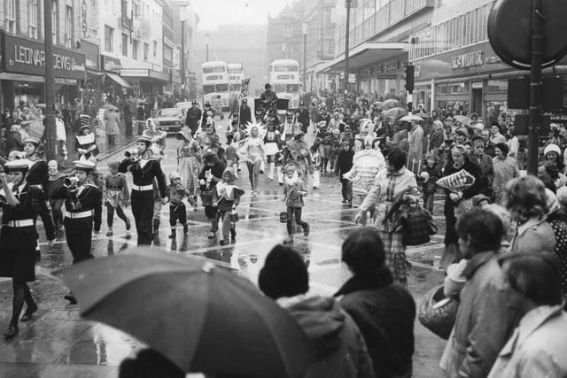 Crowds watch the annual procession of Father Christmas on his way to RHO Hills store in the rain