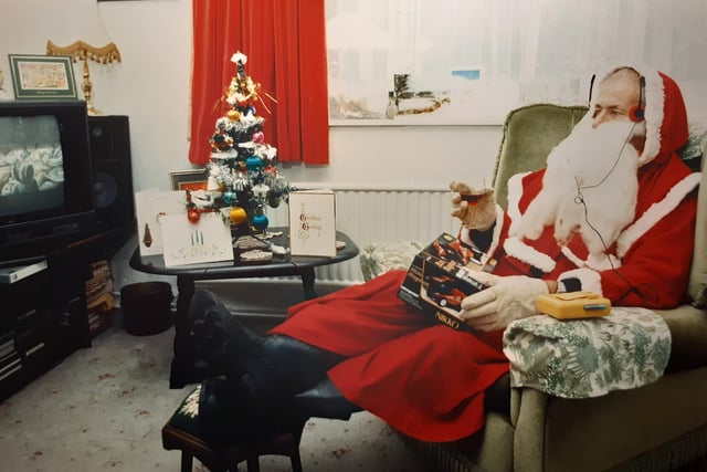 Father Christmas takes a break ahead of the big day in 1989 with his glass of port, Walkman, vintage Christmas tree with satin baubles whilst watching a TV with what looks like no remote control. Those were the days!