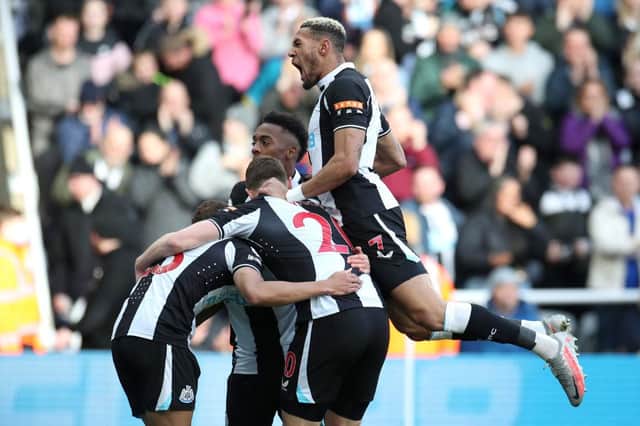 Ryan Fraser (obscured)  celebrates with teammates Joe Willock and Joelinton of Newcastle United after scoring their team's first goal during the Premier League match between Newcastle United and Brighton & Hove Albion at St. James Park on March 05, 2022 in Newcastle upon Tyne, England. (Photo by Ian MacNicol/Getty Images)