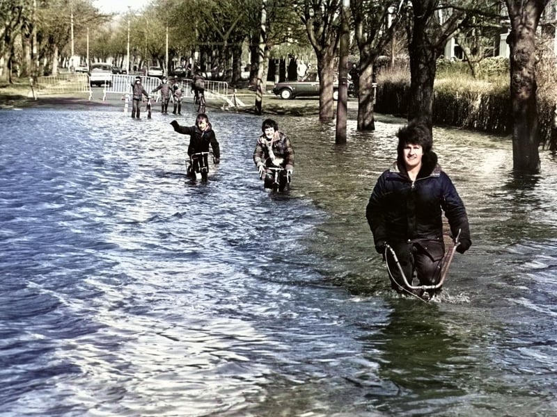 A colourised picture of kids making the most of a flooded East park Drive in 1981