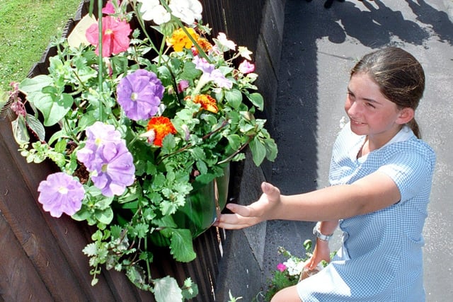 Ten year old Gemma Clement (Staining CE School) - one of the Fylde in Bloom poster competition winners- puts up the first of the hanging baskets, made by children in Staining village, for the Staining in Bloom competition
