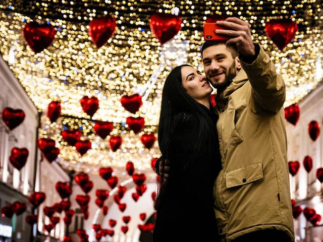 A couple poses for a selfie under heart-shaped balloons displayed for Valentine's Day in downtown Moscow on February 13, 2020. (Photo by Dimitar DILKOFF / AFP) (Photo by DIMITAR DILKOFF/AFP via Getty Images)