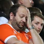 A Blackpool fan rubs his face after the third goal is conceded