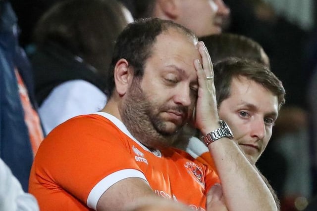 A Blackpool fan rubs his face after the third goal is conceded