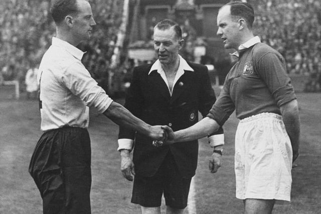 Referee Jack Barrick  looks on as Manchester United Football Club team captain Johnny Carey and Harry Johnston, team captain for Blackpool FC (left) shake hands before the kick off of their FA Cup Final match on on 24th April 1948 at Wembley.