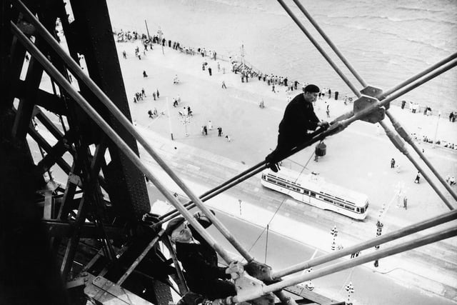 Blackpool Tower celebrates its 130th anniversary next year. At a dizzying height, without a safety harness or hard hat in sight, intrepid painters are at work on the tie-rods that brace its huge girders in September 3 1958. Photo: PA Images/Alamy Stock Photo
